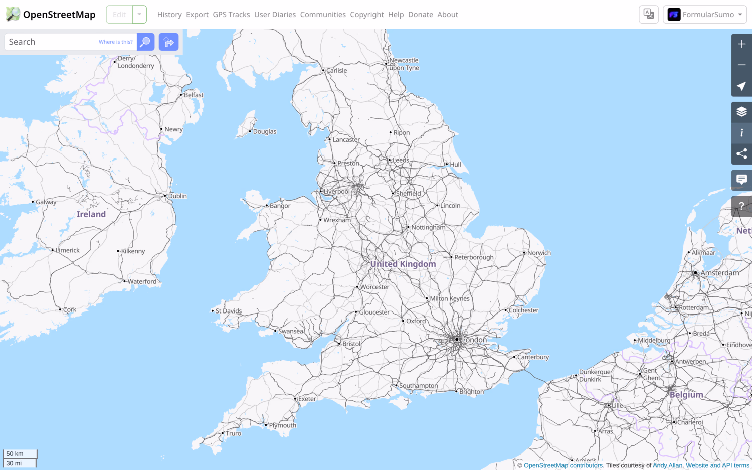 Screenshot of OpenStreetMap showing most of the UK on transport view. All existing rail lines are shown in black while roads are shown in a very light grey. Major cities are labelled with a black dot, and country and border names are purple.